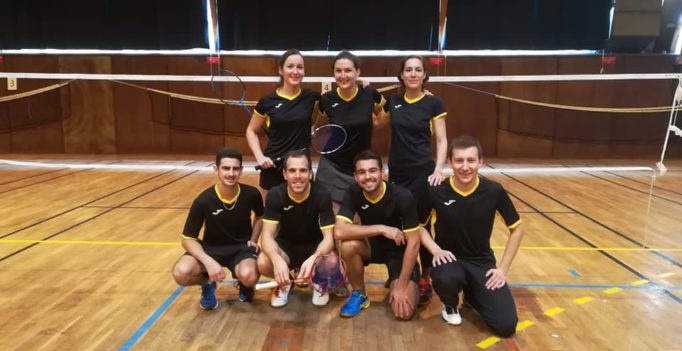 Photos de 7 joueurs de badminton de l'équipe des chartrons sur un terrain de badminton habillés en noir et jaune. Devant 4 hommes accroupis, derrière 3 femmes debout